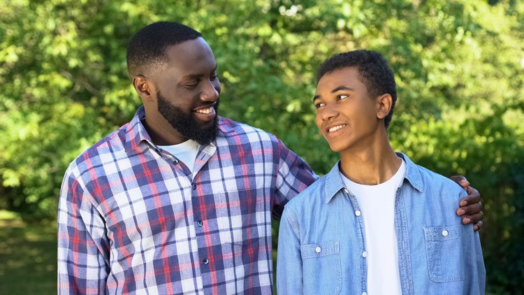 handsome Black man with his arm around his young teenage son - mental health and children